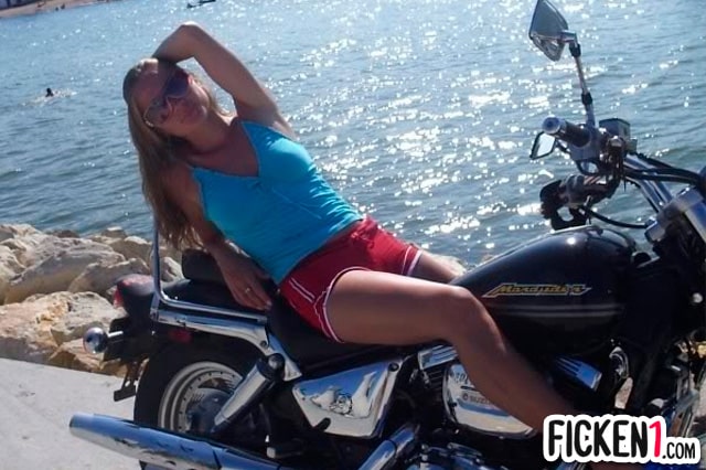 Heiße Bikerin in Sommerkleidung auf Motorrad am Strand